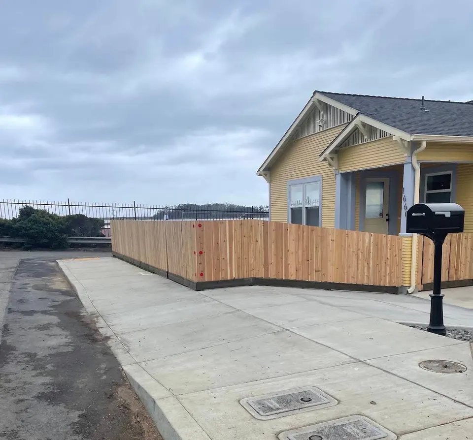 New cedar fence wrapping the front yard of a craftsman cottage by the sidewalk
