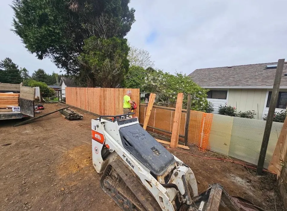 Deep Roots crew and mini skid steer mid-build on a new backyard privacy fence