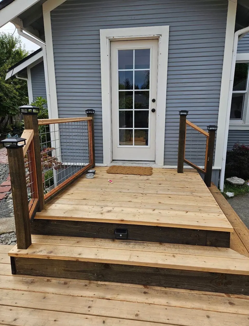 New wood entry deck and steps with hog-wire railing panels at a back door