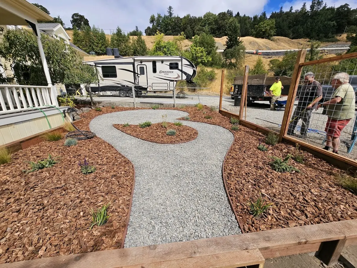 Curving gravel path bordered by steel edging and new planting beds