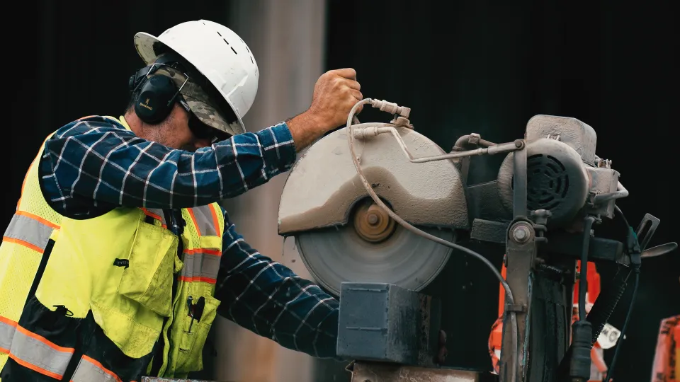 Crew member making a cut with a masonry saw during hardscape installation