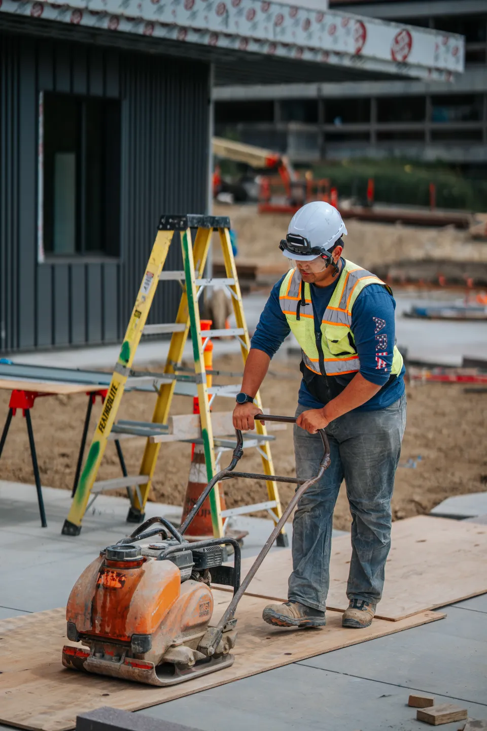 Crew member grading and screeding base material ahead of paver installation