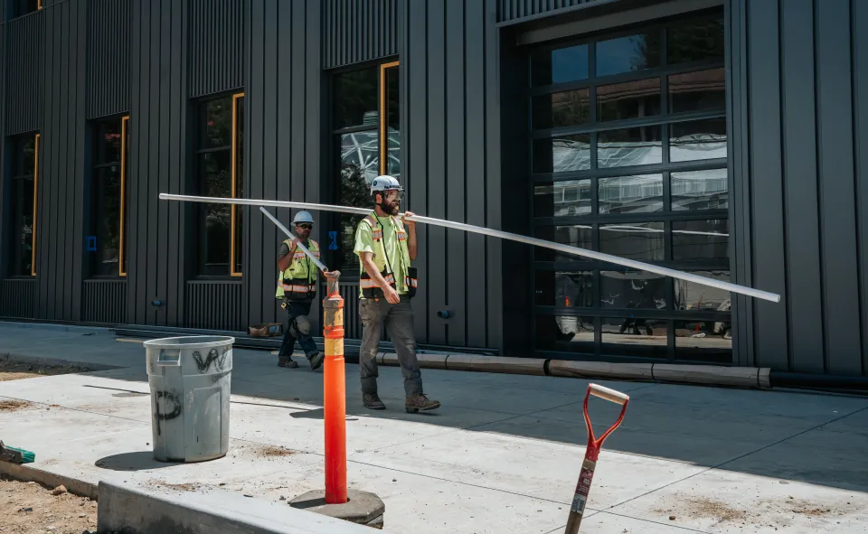 Crew carrying material across a finished concrete walkway at a commercial building