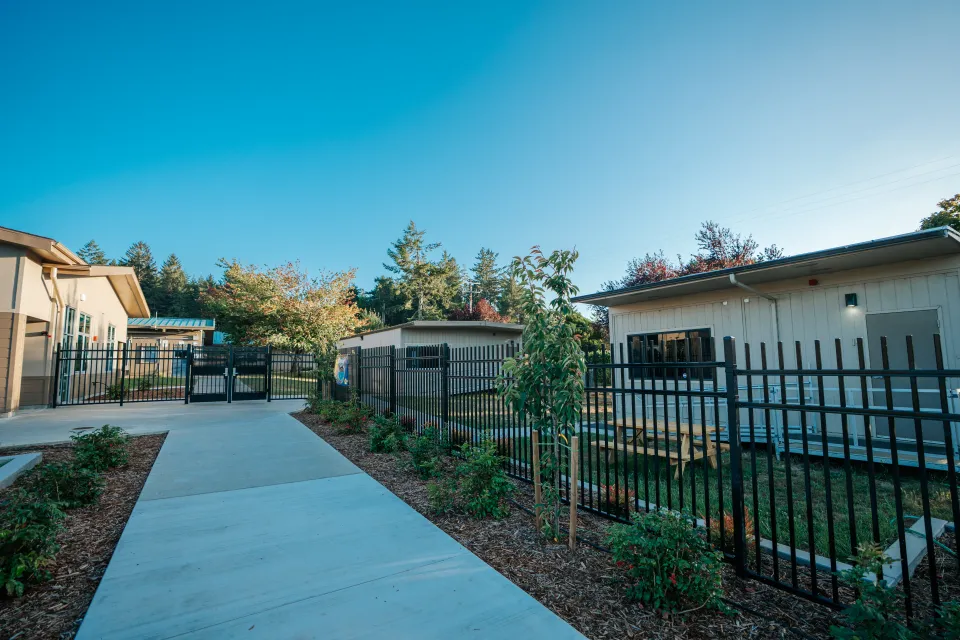 Security fence and concrete walkway running alongside new landscape beds