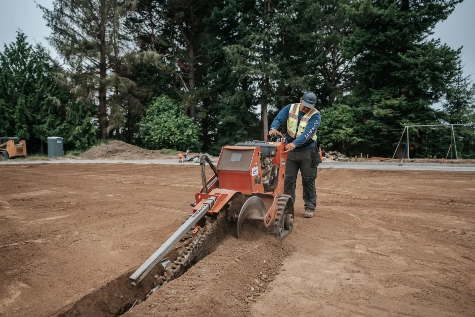 Walk-behind trencher cutting a trench for irrigation pipe on a commercial site